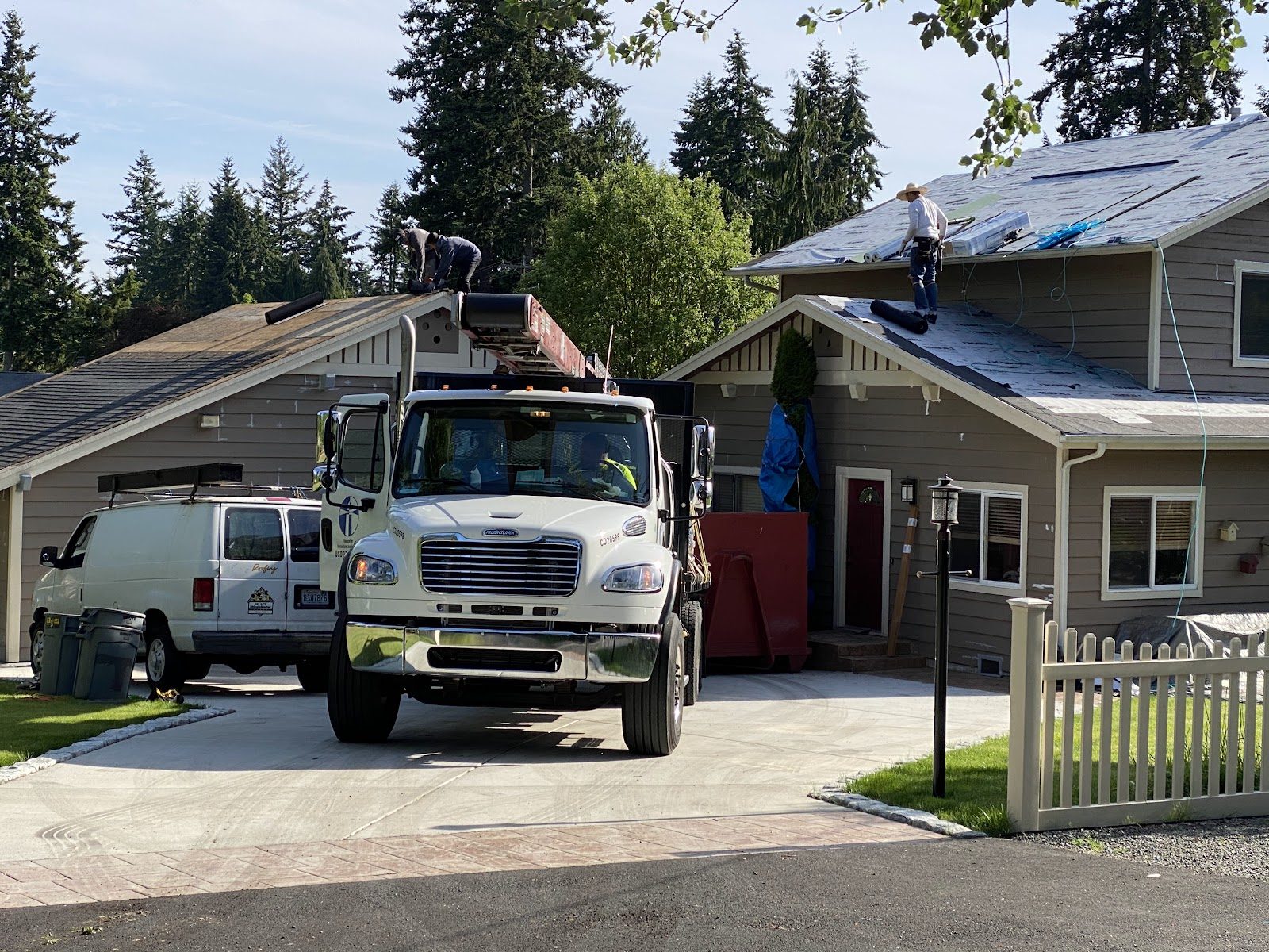 Mass & Mass crew papering two roofs at once with the conveyor truck in the driveway