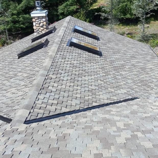 New architectural shingle roof with skylights and stone chimney